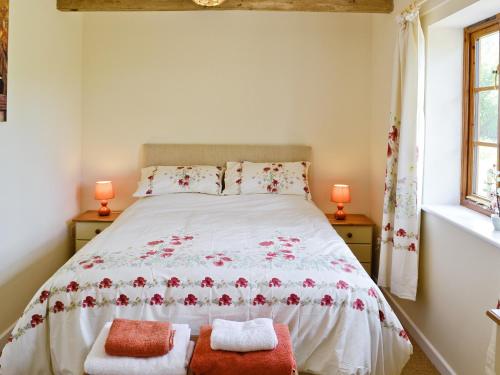 a bedroom with a bed with two pillows and two windows at Woodlanders - 29954 in Wootton Glanville