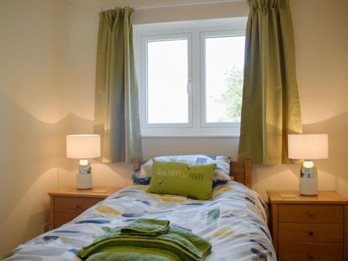 a bedroom with a bed with two lamps and a window at Meadow View in Harley