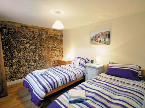 ケッシングランドにあるShrimp Cottage - E5415のレンガの壁、ベッド2台が備わるベッドルーム1室が備わります。