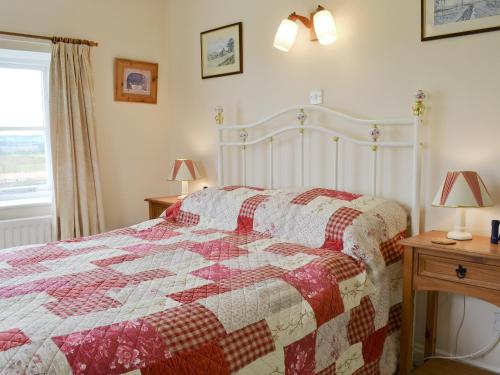 a bedroom with a bed with a red and white quilt at Manor Cottage in Old Byland