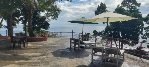 a patio with tables and chairs and an umbrella at Adhvasaha Beach Spa Resort in Port Blair