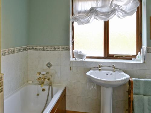 baño con lavabo, bañera, lavabo y ventana en Ye Olde Smithy, en Burythorpe