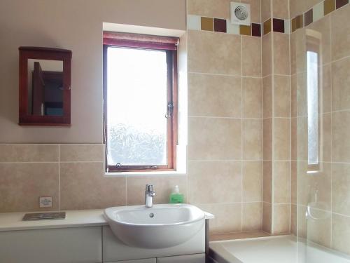 baño con lavabo, bañera y ventana en Kays Cottage, en Buckfastleigh