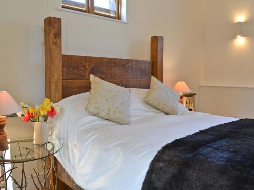 a white bed with a wooden headboard and a glass table at Fig Cottage in Brabourne