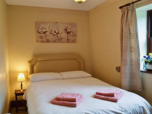 a bedroom with two pink towels on a bed at Ellarbeck Cottage in Caldbeck