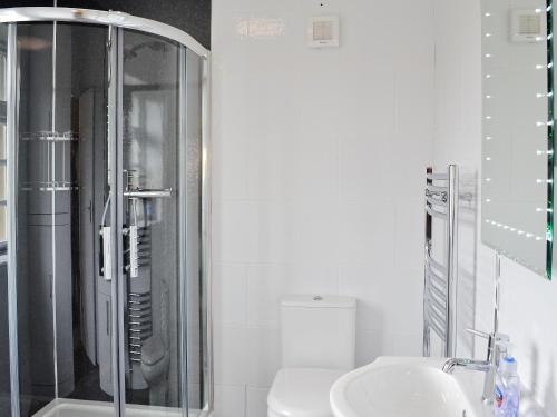 een badkamer met een douche, een wastafel en een toilet bij Windways in Port Erin