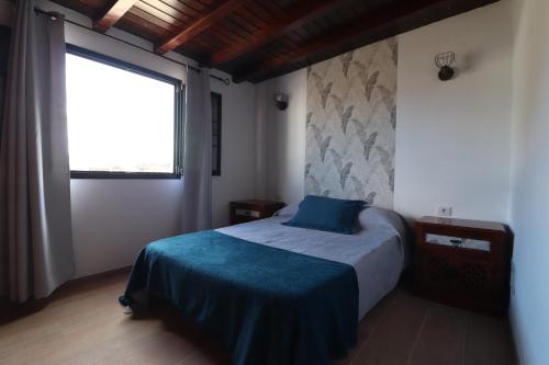 een slaapkamer met een bed met een blauwe deken en een raam bij CASA los senderos in Tinguatón