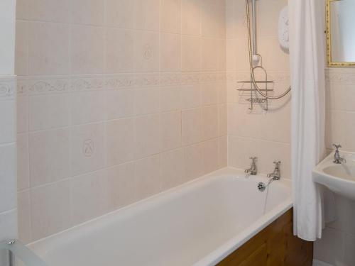 een badkamer met een wit bad en een wastafel bij Paddock Cottage in Alnwick