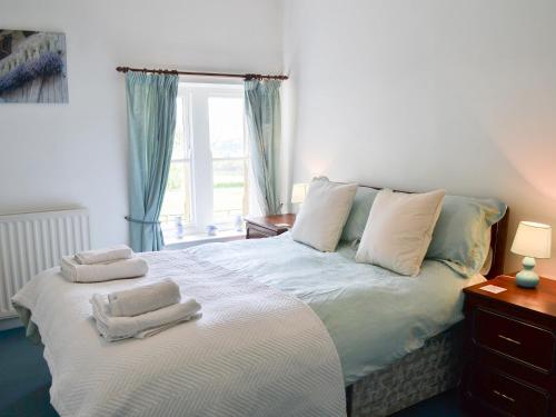 a bedroom with a large bed with towels on it at Paddock Cottage in Alnwick