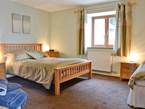 a bedroom with a bed and a window at West Rose Barn in Pendine