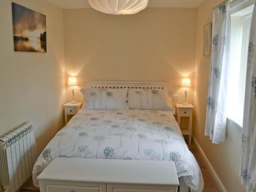 a bedroom with a white bed with two lamps at Dog Rose Cottage in Great Dunham