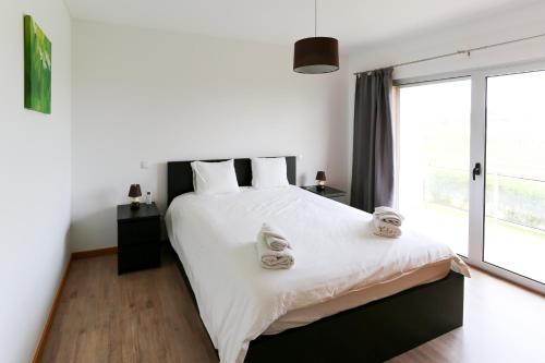 een slaapkamer met een groot wit bed met handdoeken erop bij Carmona G in São Martinho do Porto