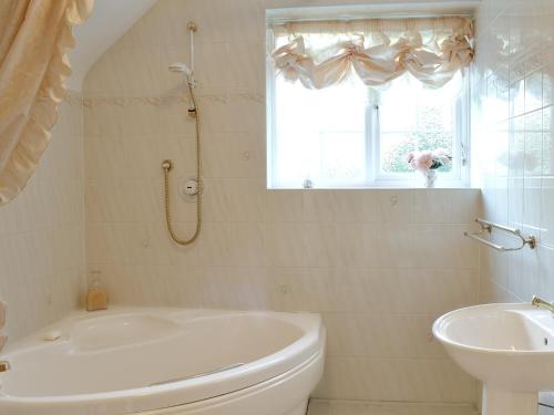 ein Bad mit einer Badewanne, einem WC und einem Fenster in der Unterkunft Laurel Cottage in Sway
