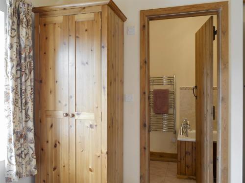 baño con puerta de madera y lavamanos en Stable Cottage, en East Meon