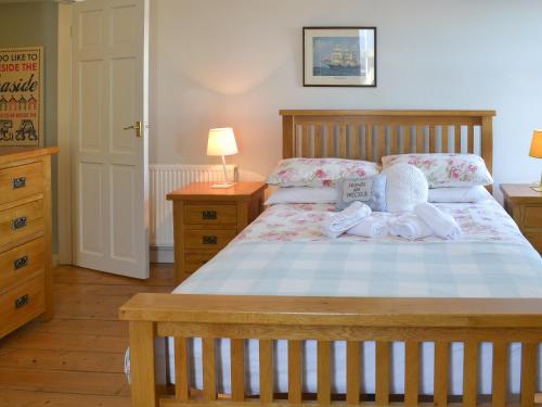 a bedroom with a wooden bed with two pillows at Providence Cottage in Turnchapel