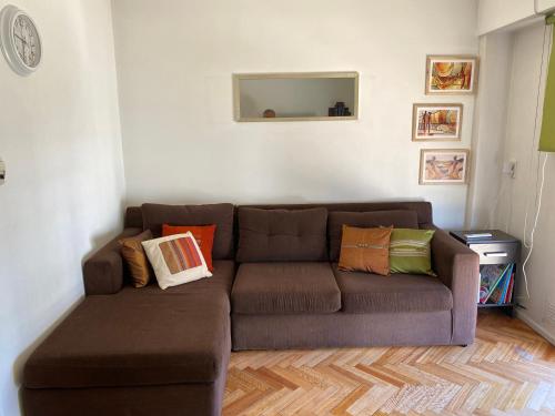 ein Wohnzimmer mit einem braunen Sofa und bunten Kissen in der Unterkunft Acogedor departamento en Caballito in Buenos Aires