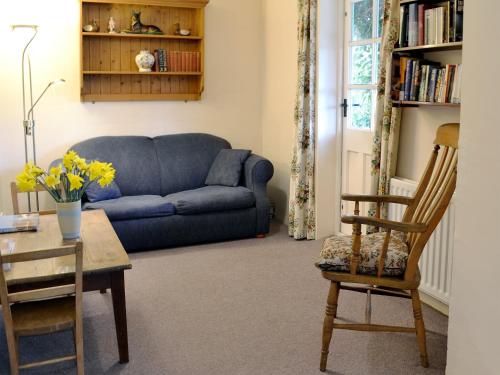 a living room with a blue couch and a table and chairs at Dill Hundred Cottage in Warbleton