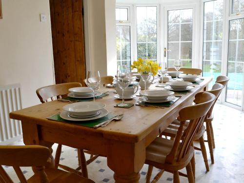 a wooden table with chairs and plates and wine glasses at Dill Hundred Cottage in Warbleton