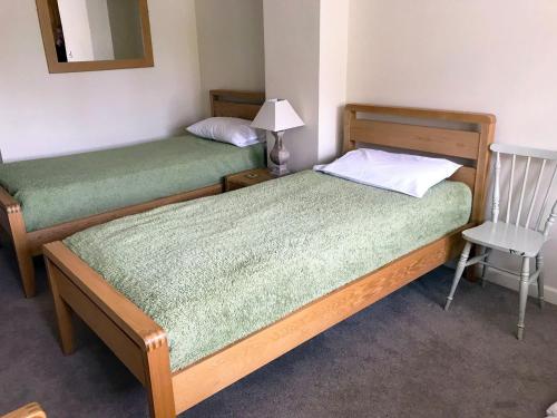 two twin beds in a room with a chair at Grooms Cottage - E5398 in Dunstall