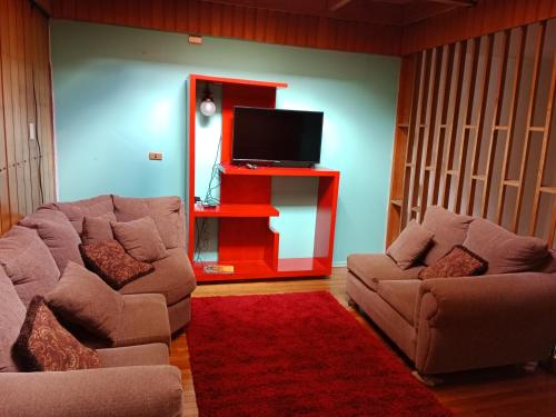 a living room with two couches and a flat screen tv at Hostal CASITA ESPAÑOLA in Castro