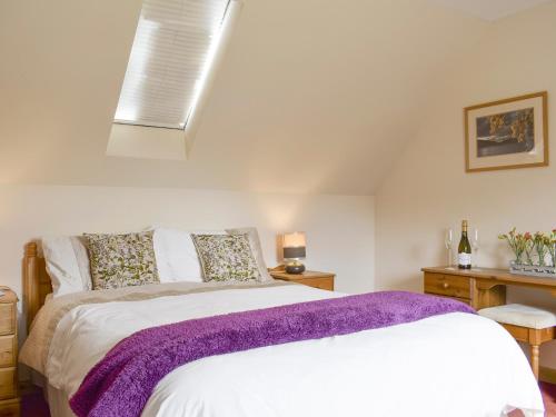 Kepculloch的住宿－The Stables - Uk5532，一间卧室配有一张带紫色毯子的床