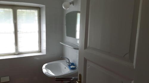 a white bathroom with a sink and a window at Jägerhaus in Hintersee