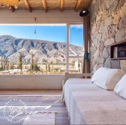 a bedroom with a large window with a mountain view at Cabañas El Mirador de Tilcara in Tilcara