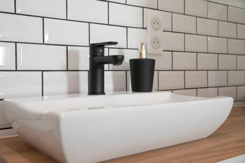 a white sink in a bathroom with white tiled walls at Le Maleville - Appartements de Standing in Périgueux