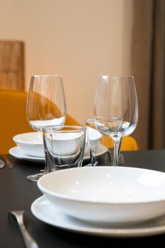 a table with three wine glasses and plates on it at Le Maleville - Appartements de Standing in Périgueux