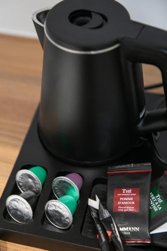 a black coffee pot sitting on top of a table at Le Maleville - Appartements de Standing in Périgueux
