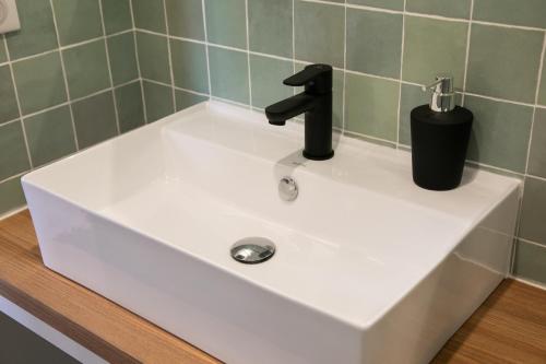 a white sink with a black faucet in a bathroom at Le Maleville - Appartements de Standing in Périgueux