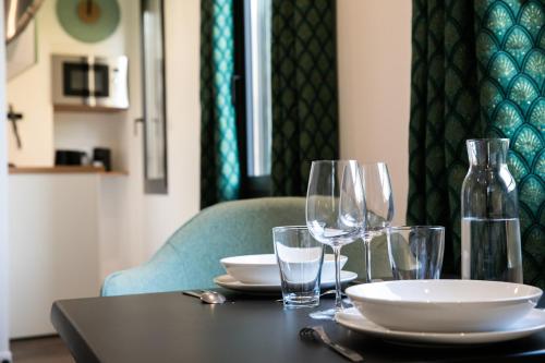 a black table with glasses and plates on it at Le Maleville - Appartements de Standing in Périgueux