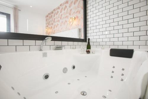 a white bath tub in a bathroom with a mirror at Le Maleville - Appartements de Standing in Périgueux