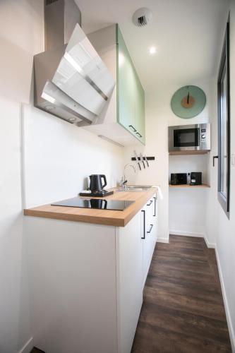 a small kitchen with white cabinets and a sink at Le Maleville - Appartements de Standing in Périgueux