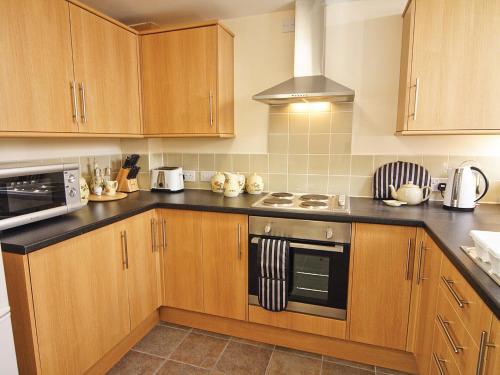 a kitchen with wooden cabinets and a stove top oven at Stable Barn - Hw7591 in Bettws-yn-Rhôs