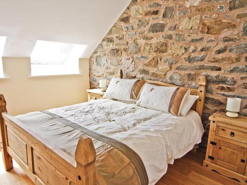 a bedroom with a bed with a stone wall at Stable Barn - Hw7591 in Bettws-yn-Rhôs