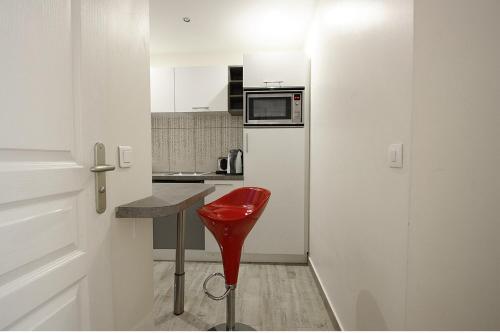 - un tabouret rouge dans une petite cuisine équipée d'un four micro-ondes dans l'établissement Bridgestreet Champs-Elysées, à Paris