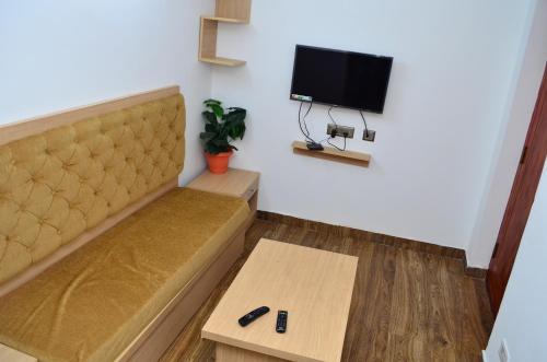 Cette chambre dispose d'un canapé, d'une table et d'une télévision. dans l'établissement HILLINGTON COTTAGE, à Kodaikānāl