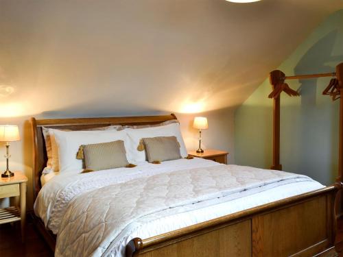 a bedroom with a large white bed with two lamps at Grange Farm Cottage in Barton in the Clay