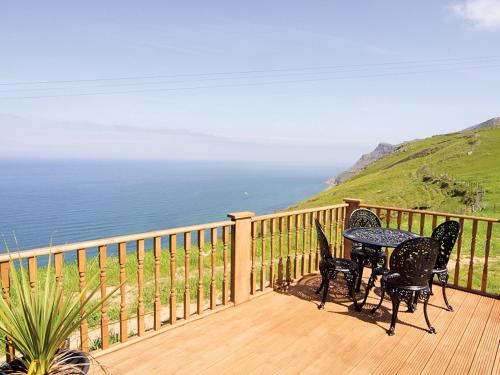 a balcony with a table and chairs and the ocean at Ciliau Isaf - Hw7680 in Pistyll