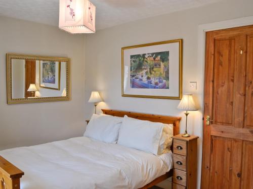 een slaapkamer met een bed, 2 lampen en een spiegel bij Dunardry View in Lochgilphead