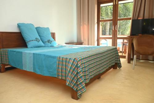 Schlafzimmer mit einem Bett mit blauer Bettwäsche und einem Fenster in der Unterkunft JAGA HOME in Tangalle