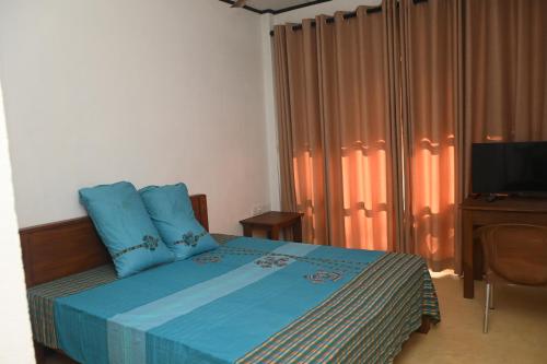 ein Schlafzimmer mit einem Bett mit blauen Kissen und einem TV in der Unterkunft JAGA HOME in Tangalle