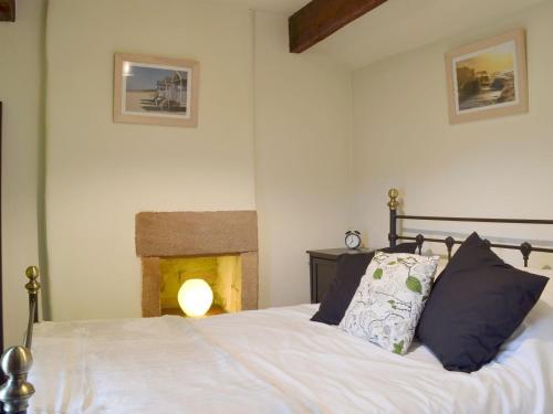 a bedroom with a white bed with a fireplace at Cornerpin Cottage in Crich