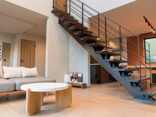 a living room with a staircase with a couch and a table at Rakuten STAY Fuji Kawaguchiko Station - Japanese Modern Villa Mt Fuji View 104 in Fujikawaguchiko