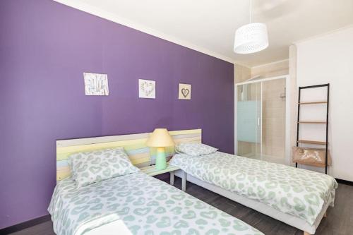 um quarto com 2 camas e uma parede roxa em villa vigneronne em Saint-Hilaire-de-Brethmas
