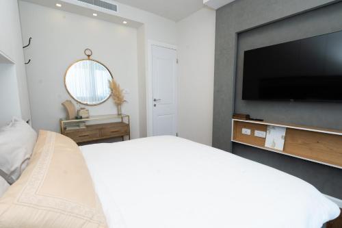 a bedroom with a flat screen tv and a bed at neot golf kz place in Caesarea