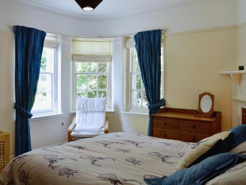 a bedroom with a bed and a chair and windows at Dunlappie Lodge in Edzell
