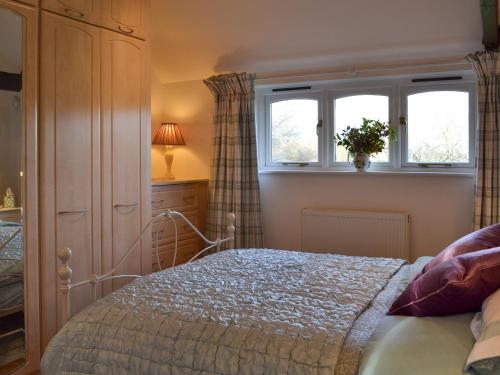 a bedroom with a bed and two windows at Maplehurst Barn Stables in Staplehurst