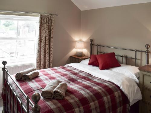 um quarto com uma cama com um cobertor vermelho e branco em Halfehill Cottage em Richmond